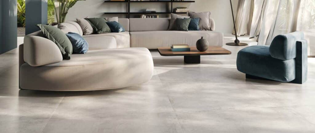 Carrelage Gris Aspect Béton pour un Salon Design et Moderne Salon moderne avec canapé beige, fauteuil bleu et carrelage gris clair aspect béton. Décoration épurée et lumineuse.